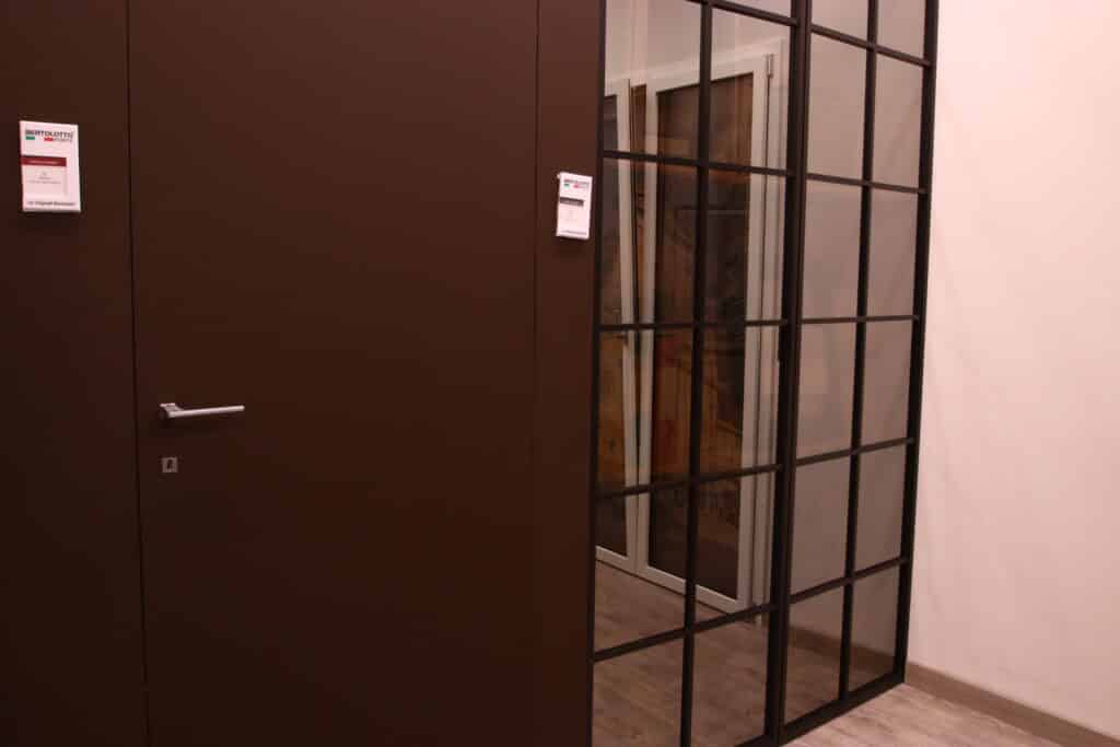 Porta marrone accanto a divisorio in vetro.