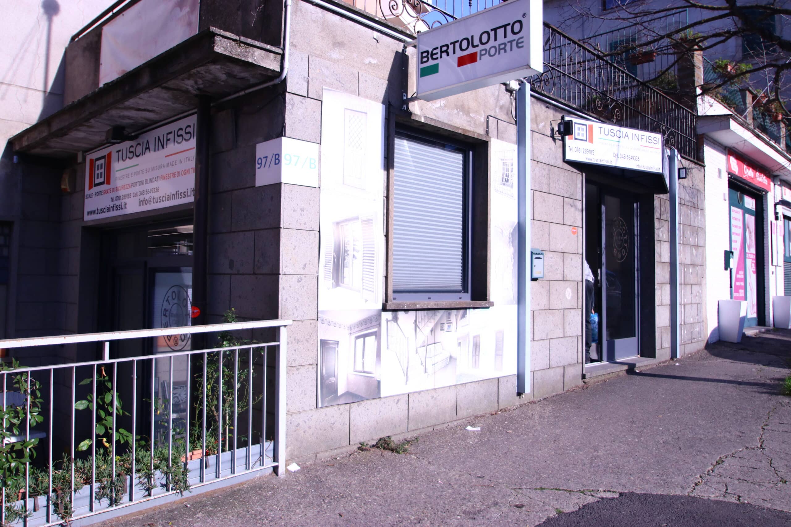 Ingresso di negozio con insegne "Tuscia Infissi" e "Bertolotto Porte".